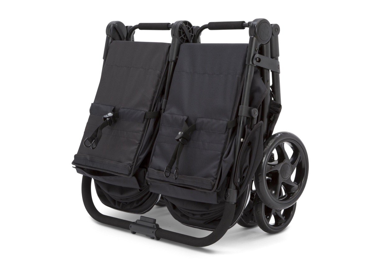 Official Delta Children product-page photo of the same stroller collapsed into its compact standing fold, standing upright for storage or trunk loading