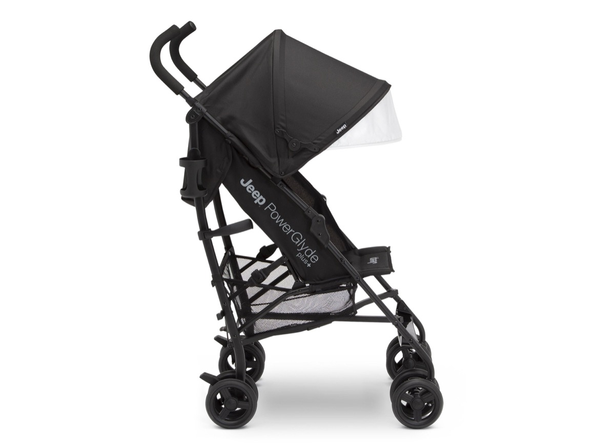 Official Delta Children product-page side-profile photo of the Jeep PowerGlyde Plus Stroller in Black (001), unfolded, showing the PowerGlyde Plus frame branding, the recline hinge line, the extendable canopy, and the mesh storage basket, against a white background