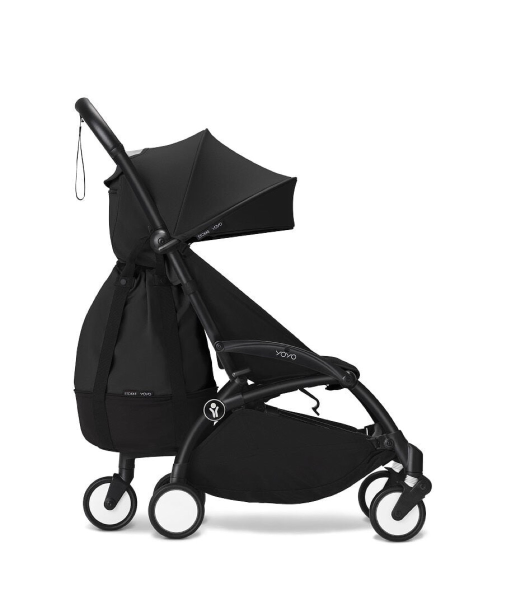 Black/Black YOYO3 6+ stroller unfolded with a black Stokke YOYO shoulder bag hanging on the backrest, side profile on a white studio background.